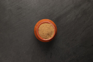 cumin coriander seed powder in a small clay ceramic pot on a dark slate surface with a clean and neat appearance striking contrast vibrant spice