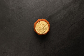 Asian spice mix powder blend in small clay ceramic pot on a dark slate surface with a clean and neat appearance striking contrast vibrant spice top view flat lay