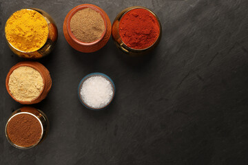Overhead top view flat lay colourful array of spices herbs powder blue clay ceramic brass metal pot...