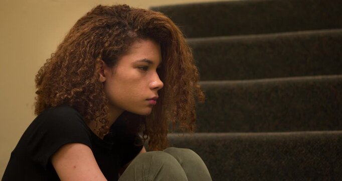 Female upset and depressed sitting curled up on steps 4k