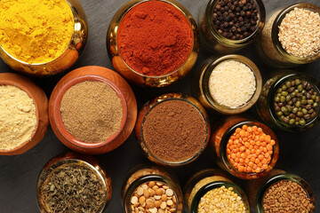 Overhead top view flat lay colourful array of spices herbs powder blue clay ceramic brass metal pot...