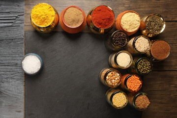 Overhead top view flat lay colourful array of spices herbs powder blue clay ceramic brass metal pot...