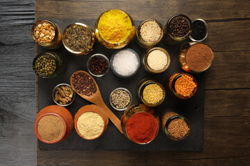 Overhead top view flat lay colourful array of spices herbs powder blue clay ceramic brass metal pot...
