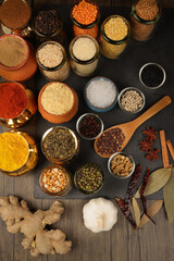 Overhead top view flat lay colourful array of spices herbs powder blue clay ceramic brass metal pot on dark black slate surface with a clean and neat appearance spice copy text space border frame
