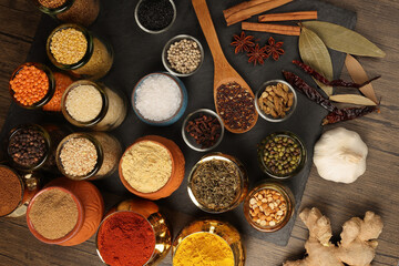 Overhead top view flat lay colourful array of spices herbs powder blue clay ceramic brass metal pot...
