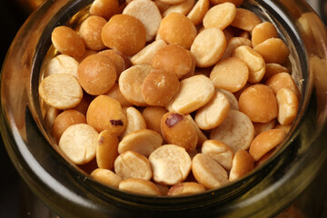 Top down flat lay view of split peas chana buter dal in mini glass jar on dark black slate background