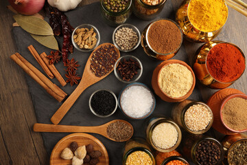 Overhead top view flat lay colourful array of spices herbs powder blue clay ceramic brass metal pot on dark black slate surface with a clean and neat appearance spice copy text space border frame