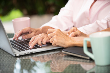 Retirement learning technology activities friends senior couple hands laptop home comfort support focus connection coffee table morning