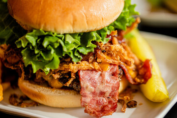  A handcrafted beef burger with bacon with a pickle at a trendy restaurant 