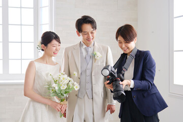 笑顔で会話する新郎新婦とブライダルフォトグラファー