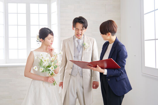 悩みながら打ち合わせする結婚式の司会者と新郎新婦