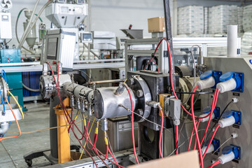 Plastic extrusion machine with cables and control unit at modern manufacturing plant.
