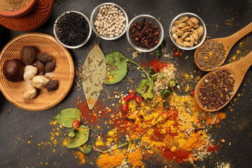 Overhead flat lay vibrant colourful spices herbs fresh produce vegetables legumes on wooden table spread splash smoking spice mix dark black slate metal clay pot palm leaf plate board copy text frame
