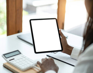Businesswoman at office desk holding a tablet with a blank white screen mockup for app or website display