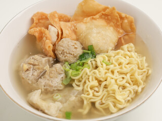 Meatball soup with noodles and fried dumpling in white bowl