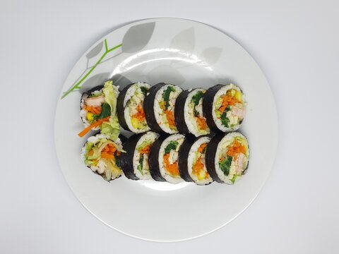 Small serving of Korean kimbap on a clean white plate, perfect for minimalist food presentation.