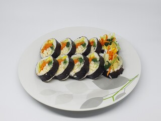 Freshly sliced Korean kimbap rolls with colorful vegetables and rice served on a white dish.