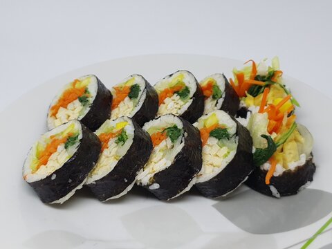 Homemade Korean kimbap rolls filled with egg and vegetables arranged side by side on a clean plate.
