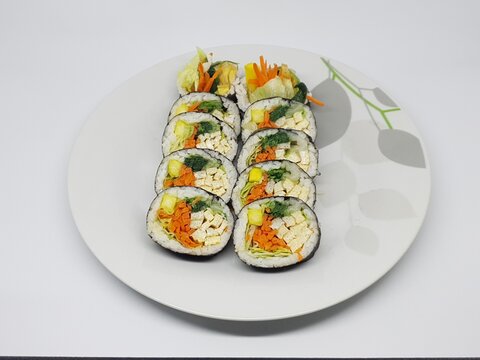 Kimbap rolls filled with vegetables and egg neatly arranged on a white plate with clean minimal background.
