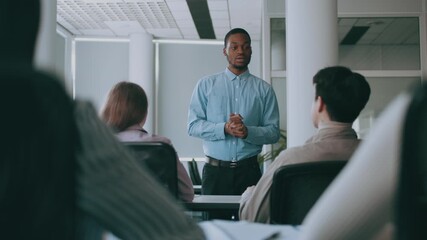 A group of diverse college students listens attentively to an instructor during a lecture in a contemporary classroom. The atmosphere is focused, encouraging active participation and learning.