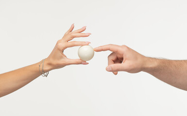 white round object in hands. a finger points to a white empty ball in a woman's palm