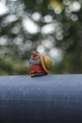 a toy cat wearing a hat is sitting in nature