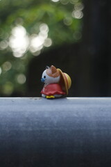 a toy cat wearing a hat is sitting in nature