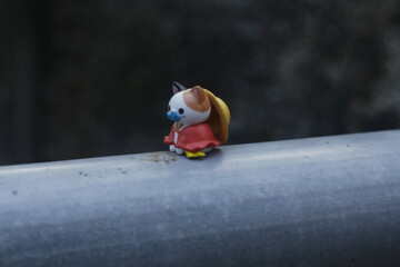 a toy cat wearing a hat is sitting in nature