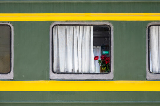 Green Train Carriage Window With White Curtains And Red Roses Inside