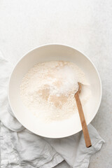 Overhead view of ingredients for making english muffin bread dough in a bowl, process of making english muffin bread