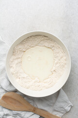 Overhead view of ingredients for making english muffin bread dough in a bowl, process of making english muffin bread