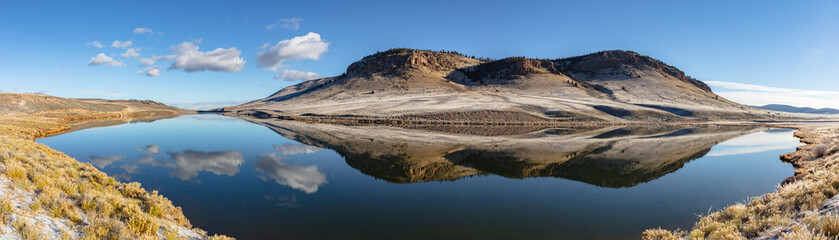 Autumn morning Colorado landscape panorama featuring the base of Cochetopa Dome reflecting in Dome Reservoir. 