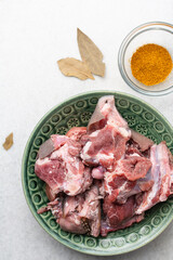 Overhead view of mise en place of ingredients and spices for cooking raw goat meat, top view of chopped goat meat being prepared for cooking	