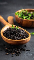 Black tea in wooden spoon, thyme in wooden bowl