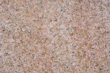 ピンクがかった石のざらざらした表面のクローズアップ。凹凸少なめ。石や岩のテクスチャー