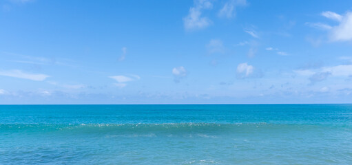 Fototapeta premium Deep blue sea and wave with blue sky and thin fluffy clouds taken at the sea in Phuket South of Thailand used as blue natural background texture