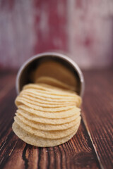 Stack of chips spilling from a can onto a wooden table