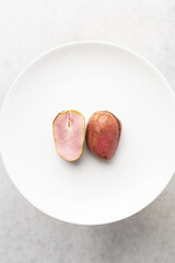 Overhead view of open kola nut on white granite countertop, top view of fresh split kolanut on a white plate