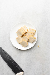 Overhead view of sliced firm tofu, top view of slices of soya bean tofu on a white plate