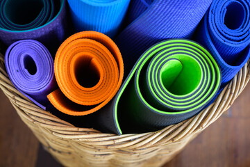 Various coloured yoga mats rolled up - horizontal