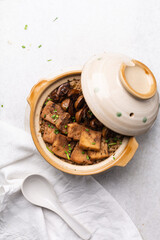 Overhead view vegan claypot rice with pan fried tofu, mushrooms and scallions, top view of crispy rice in a donabe on a marble countertop