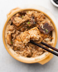 Overhead view of vegan claypot rice with pan fried tofu in chopsticks, top view of crispy rice in chopsticks
