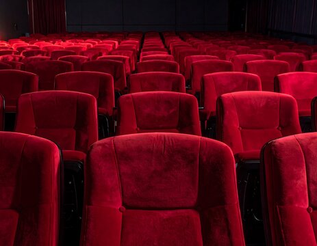 Rows of plush, red velvet seats in an empty movie theater, viewed head-on - Powered by Adobe