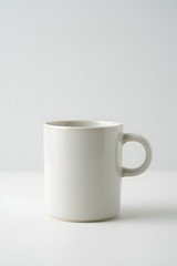 Obraz premium Minimalist white ceramic mug with a round handle on a plain white background