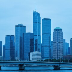 Naklejka premium Modern Cityscape With Blue Toned Skyscrapers And A Bridge Over Water In The Evening Light