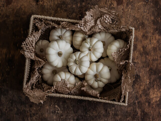 Small white decorative pumpkins in a box on a wooden background