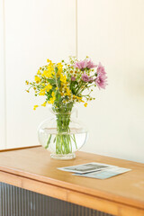 Fresh Flowers in a Glass Vase on a Wooden Cabinet with Green Fruit, beautiful bouquet of wildflowers in vase on table, stock photo