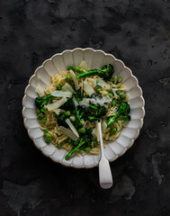 Delicious vegetarian lunch, dinner - orzo pasta with broccoli and green fresh peas on a dark background, top view