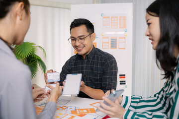 A group of UX/UI designers brainstorming creative ideas together, discussing color palettes and layout concepts for a new mobile application interface in a modern design office.