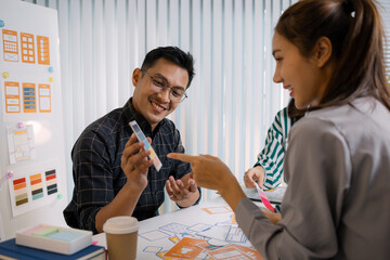 A group of UX/UI designers brainstorming creative ideas together, discussing color palettes and layout concepts for a new mobile application interface in a modern design office.